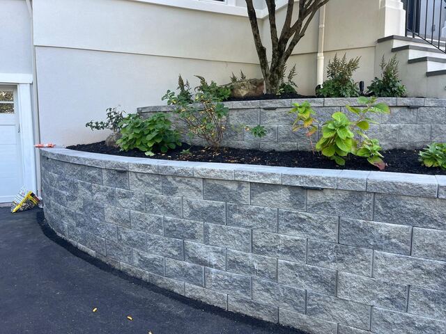 Long curved block retaining wall along asphalt driveway