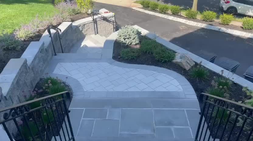 Curved bluestone walkway with stone walls and landscaped beds at a front entry