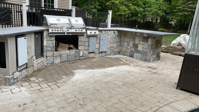 Outdoor kitchen under construction showing stone veneer and appliance openings