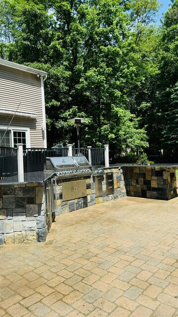Custom stone veneer outdoor kitchen with granite counter and twin built-in grills