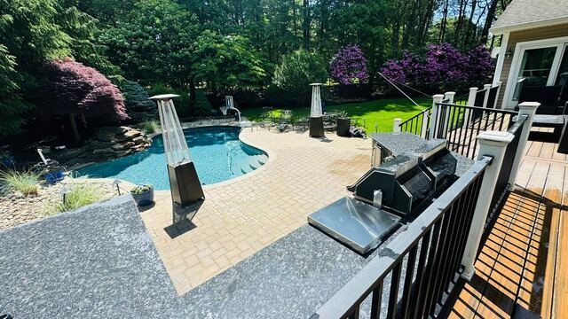 In-ground pool with paver deck, outdoor kitchen and landscaped surround