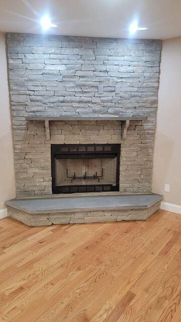 Floor-to-ceiling stacked stone fireplace with bluestone hearth and mantel shelf