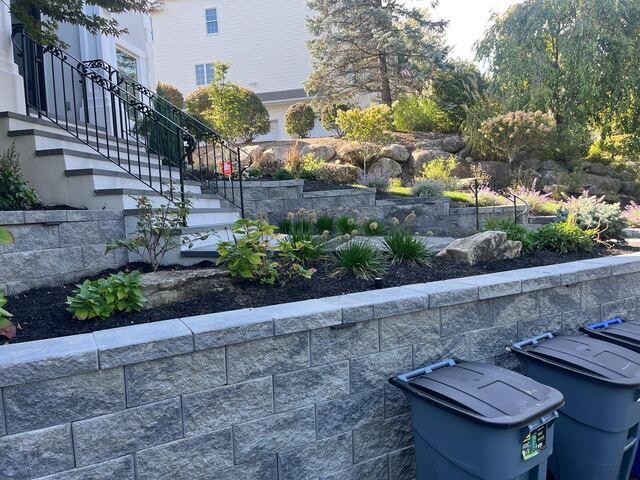 Tiered retaining walls with planted garden beds and natural rock outcropping